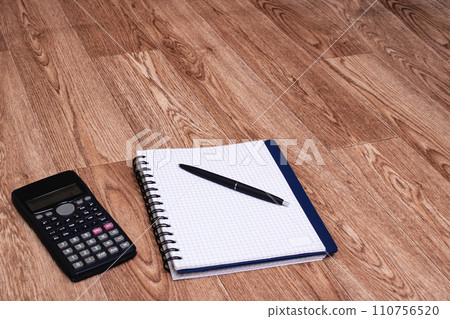 Engineering calculator, notebook and pen on wooden table 110756520