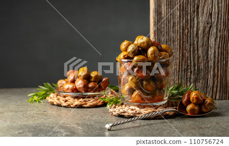 Spicy olives in a glass bowl on a stone table. 110756724