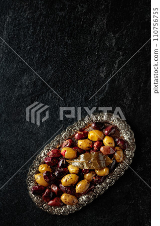Spicy olives on a black stone table. Spicy olives on a black stone table. 110756755