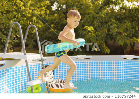 Young Boy with Inflatable Toy Entering Pool in Summer Young Boy with Inflatable Toy Entering Pool in Summer 110757244