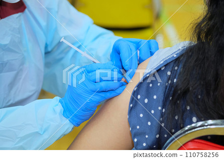 Doctor hands who is vaccinating on upper arm of people Doctor hands who is vaccinating on upper arm of people 110758256