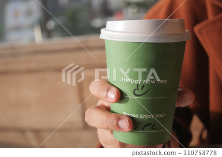 holding a take away kraft coffee cup with happy new year wish on it holding a take away kraft coffee cup with happy new year wish on it 110758778
