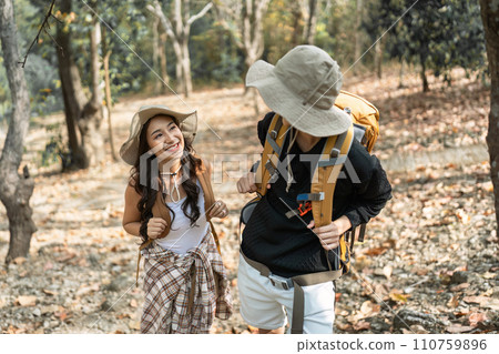 Happy LGBT Lesbian couple Travelers Hiking with Backpacks in forest Trail. LGBT Lesbian Couple Hikers with backpacks walks in mountains in vacation 110759896