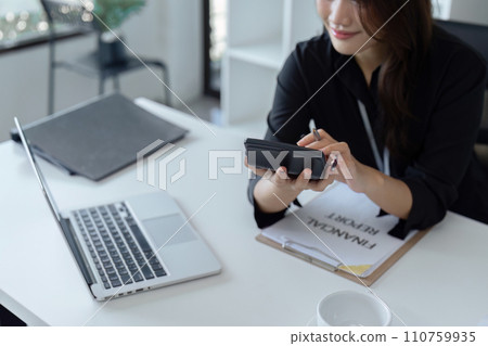 Businesswoman using a calculator to calculate numbers on a company's financial documents, she is analyzing historical financial data to plan how to grow the company. Financial concept Businesswoman using a calculator to calculate numbers on a company's financial documents, she is analyzing historical financial data to plan how to grow the company. Financial concept 110759935