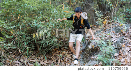 LGBTQ backpacker traveling alone in forest. Attractive male traveler walking in nature wood during holiday vacation trip 110759936