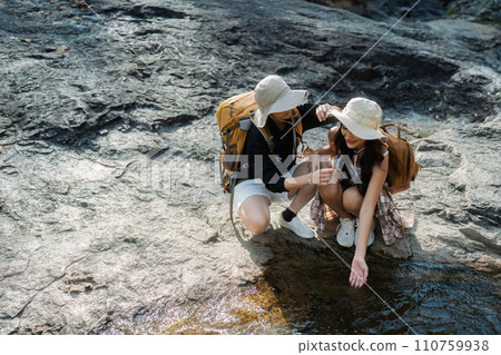 Happy LGBT Lesbian couple Travelers Hiking with Backpacks in waterfall Trail. LGBT Lesbian Couple Hikers with backpacks walks in mountains in vacation Happy LGBT Lesbian couple Travelers Hiking with Backpacks in waterfall Trail. LGBT Lesbian Couple Hikers with backpacks walks in mountains in vacation 110759938
