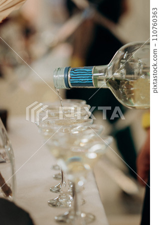 Waiter pouring martini or champagne in crystal glasses on table party at wedding reception 110760363