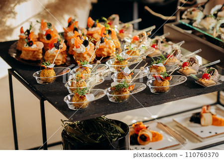 Assortment of delicious snacks on the open buffet festive table in restaurant. Catering plate 110760370
