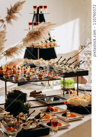 Assortment of delicious snacks on the open buffet festive table in restaurant. Catering plate Assortment of delicious snacks on the open buffet festive table in restaurant. Catering plate 110760372