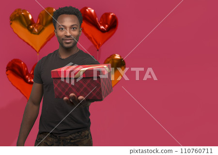 man holding gift box on pink background with heart shape balloons for valentine's day card with copy space man holding gift box on pink background with heart shape balloons for valentine's day card with copy space 110760711