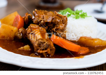 Curry pork with rice in a white plate on a wooden table Curry pork with rice in a white plate on a wooden table 110762451