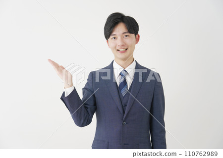 年輕商人用手掌、白色背景指著左邊 110762989