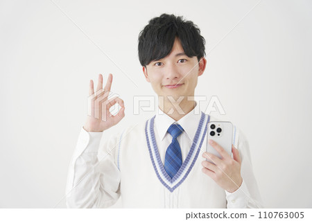 High school boy holding a smartphone and giving an OK sign, white background 110763005