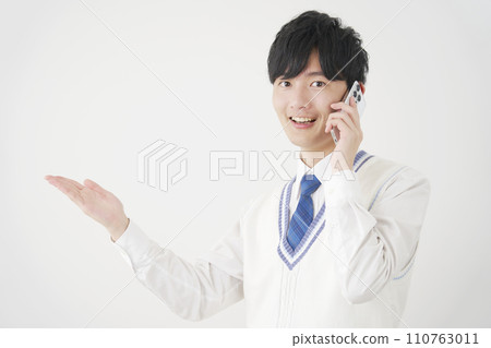 高中男孩用手掌指著左側，同時打電話給智慧型手機，白色背景 110763011
