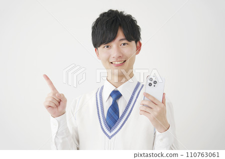 High school boy holding a smartphone and pointing to the left, white background High school boy holding a smartphone and pointing to the left, white background 110763061
