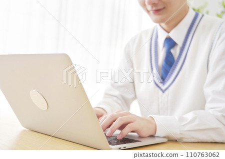 High school boy using a laptop in the living room, faceless High school boy using a laptop in the living room, faceless 110763062