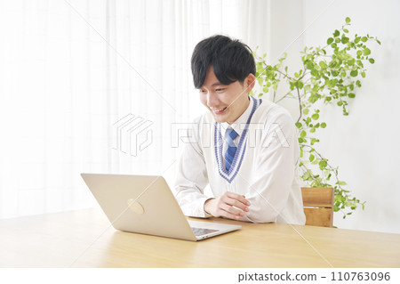 High school boy watching video on laptop in living room 110763096