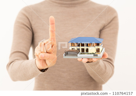 一位中年婦女拿著獨立屋模型，舉起食指 110764157