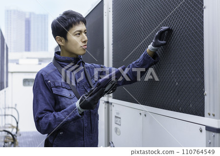 Portrait of a young man wearing denim work clothes doing inspection work on the roof of a building Photography cooperation: Ariake College of Education and Art 110764549