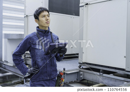 Portrait of a young man wearing denim work clothes doing inspection work on the roof of a building Photography cooperation: Ariake College of Education and Art Portrait of a young man wearing denim work clothes doing inspection work on the roof of a building Photography cooperation: Ariake College of Education and Art 110764556