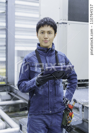 Portrait of a young man wearing denim work clothes doing inspection work on the roof of a building Photography cooperation: Ariake College of Education and Art 110764557