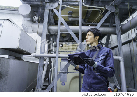 Portrait of a young man doing inspection work on the roof of a building in the light rain Photography cooperation: Ariake College of Education and Art 110764680