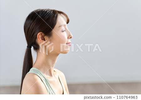 Woman meditating with eyes closed at home Woman meditating with eyes closed at home 110764963