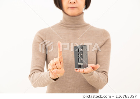 一名中年婦女手持建築房屋模型並舉起食指 110765357