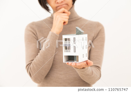 一位中年婦女拿著獨立屋的模型,憂心忡忡。 一位中年婦女拿著獨立屋的模型,憂心忡忡。 110765747