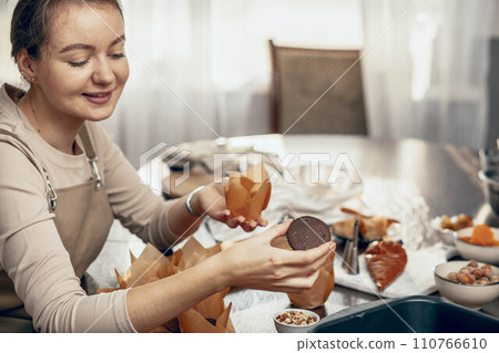 A young woman packs cupcakes in a craft. concept of food delivery. A birthday package. small business. bakery chef bakes pastries and cakes in kitchen, copy space A young woman packs cupcakes in a craft. concept of food delivery. A birthday package. small business. bakery chef bakes pastries and cakes in kitchen, copy space 110766610