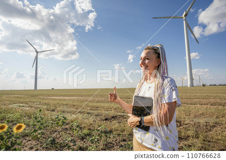 A blogger girl with bright braids shoots a story about green energy, about working with wind energy and wind turbines 110766628