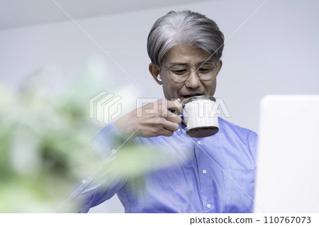 Middle-aged man drinking coffee during an online meeting 110767073