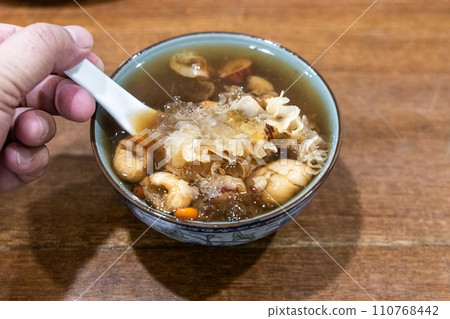 Hand with spoon scooping longan with snow fungus goji seaweed soup, popular desert among the Chinese 110768442