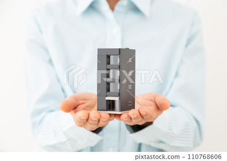 Middle-aged woman with a house model of a building 110768606