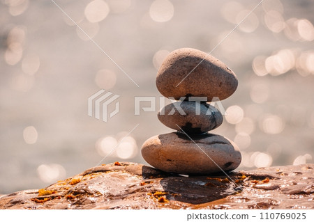 Pyramid stones on the seashore on a sunny day on the blue sea background. Happy holidays. Pebble beach, calm sea, travel destination. Concept of happy vacation on the sea, meditation, spa, calmness. 110769025