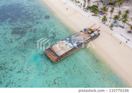 Aerial top view of construction sand cargo ship on island sea beach in the export, import business, logistics and transportation concept with international goods on the blue ocean. Aerial top view of construction sand cargo ship on island sea beach in the export, import business, logistics and transportation concept with international goods on the blue ocean. 110770286