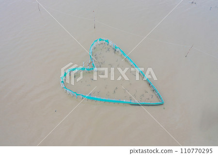 Aerial view of heart shape fishing trap net in canel urban city village town houses, lake or river. Nature landscape fisheries and fishing tools at Pak Pha, Thailand. Aquaculture farming. Love 110770295
