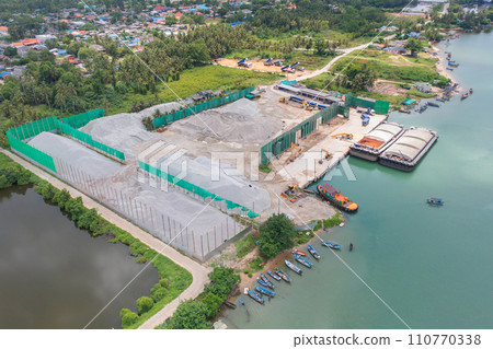 Aerial top view of concrete cement factory industry with sea. Electricity tower building in energy, transportation, logistic or environment concept. Manufacturing workshop station. Aerial top view of concrete cement factory industry with sea. Electricity tower building in energy, transportation, logistic or environment concept. Manufacturing workshop station. 110770338