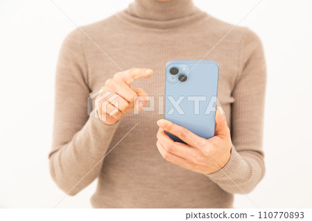 A middle-aged woman operating a smartphone 110770893