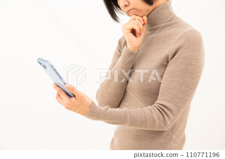 一位中年婦女在操作智慧型手機時憂心忡忡 一位中年婦女在操作智慧型手機時憂心忡忡 110771196