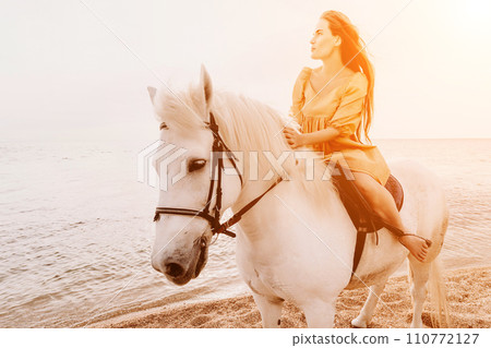 A white horse and a woman in a dress stand on a beach, with the A white horse and a woman in a dress stand on a beach, with the 110772127