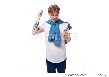 young handsome caucasian man with golden red hair with a tattoo on his arms is dressed in a white t 110772737