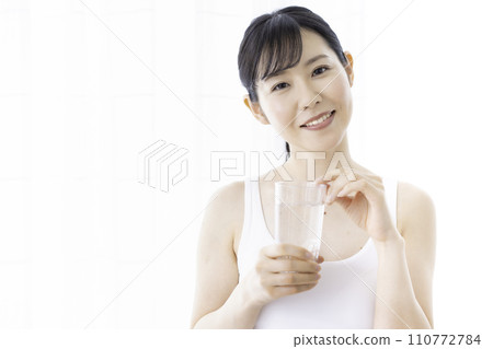woman in tank top drinking water woman in tank top drinking water 110772784