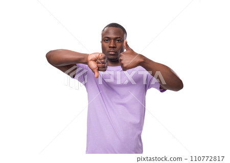 young handsome african man in lilac t-shirt having doubts showing like and dislike on white 110772817