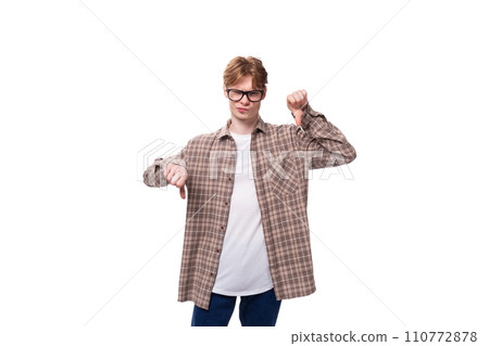 a young man with red hair dressed in a plaid shirt points with his hand to copy space 110772878