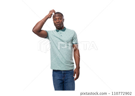 young slender American man dressed in a T-shirt and jeans thoughtfully scratches his head young slender American man dressed in a T-shirt and jeans thoughtfully scratches his head 110772902