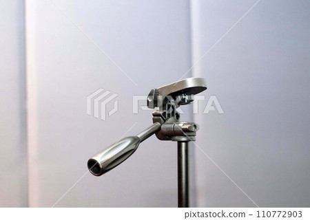 Close up a head of a tripod of camera beside white wall Close up a head of a tripod of camera beside white wall 110772903