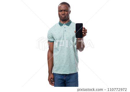 young american guy dressed in a mint t-shirt holds a smartphone in his hand with a mockup young american guy dressed in a mint t-shirt holds a smartphone in his hand with a mockup 110772972