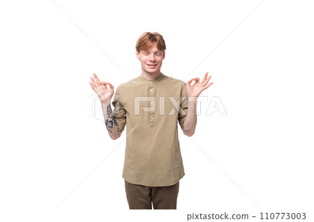 young red-haired man in a beige shirt meditates on a white background young red-haired man in a beige shirt meditates on a white background 110773003
