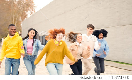 Diverse multiethnic friends laughing and running outdoors 110773788